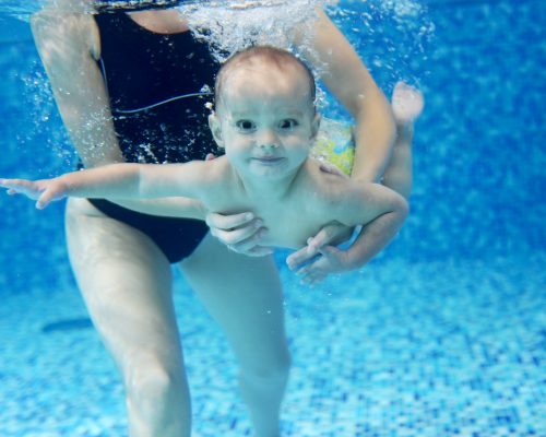 Little boy learning to swim in a swimming pool