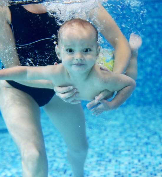 Little boy learning to swim in a swimming pool