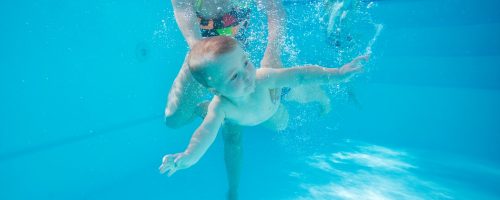 Little boy learning to swim underwater in pool